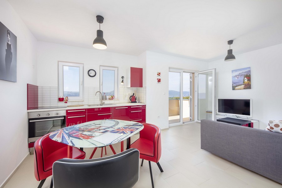 Open kitchen-living room in red and white with door to the balcony