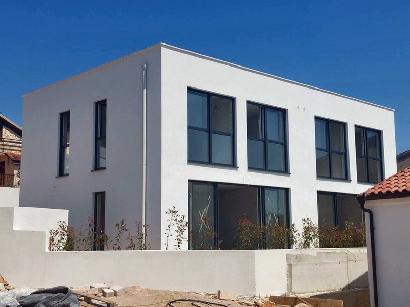 White new build with dark windows behind the wall