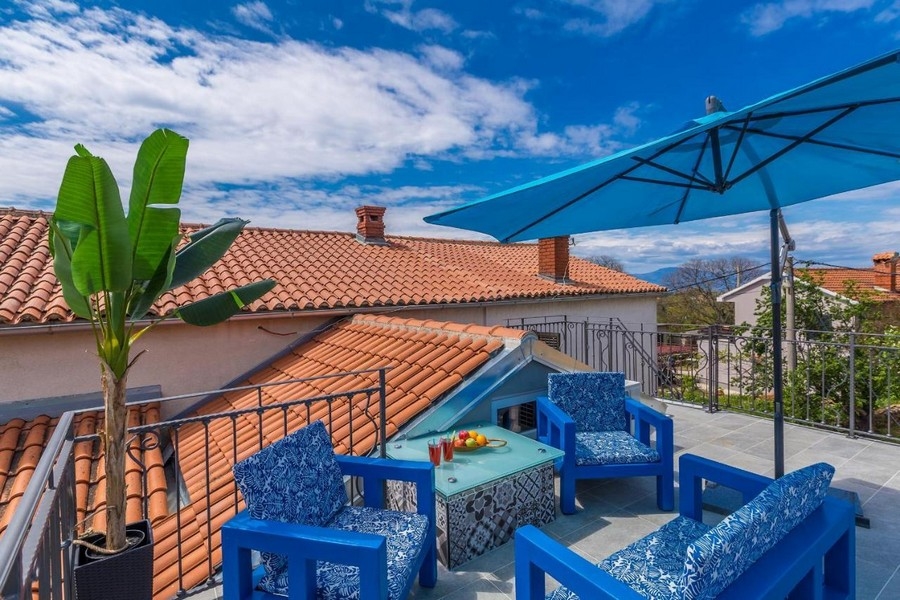 Roof terrace with blue furniture and a parasol above the tiles