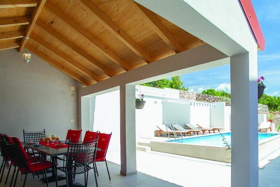 Covered dining area and view of the swimming pool.