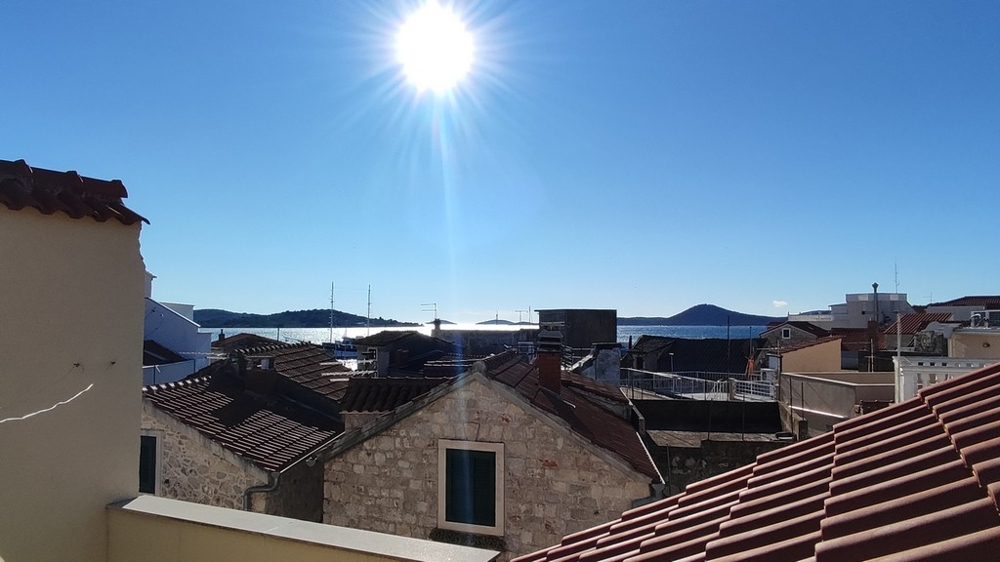 View from a townhouse in Vodice, Croatia real estate, overlooking the sea and surrounding roofs.