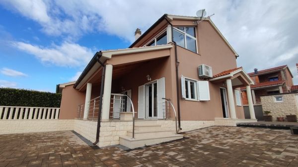 Front view of the semi-detached house for sale in Croatia with a paved driveway and a large entrance area.