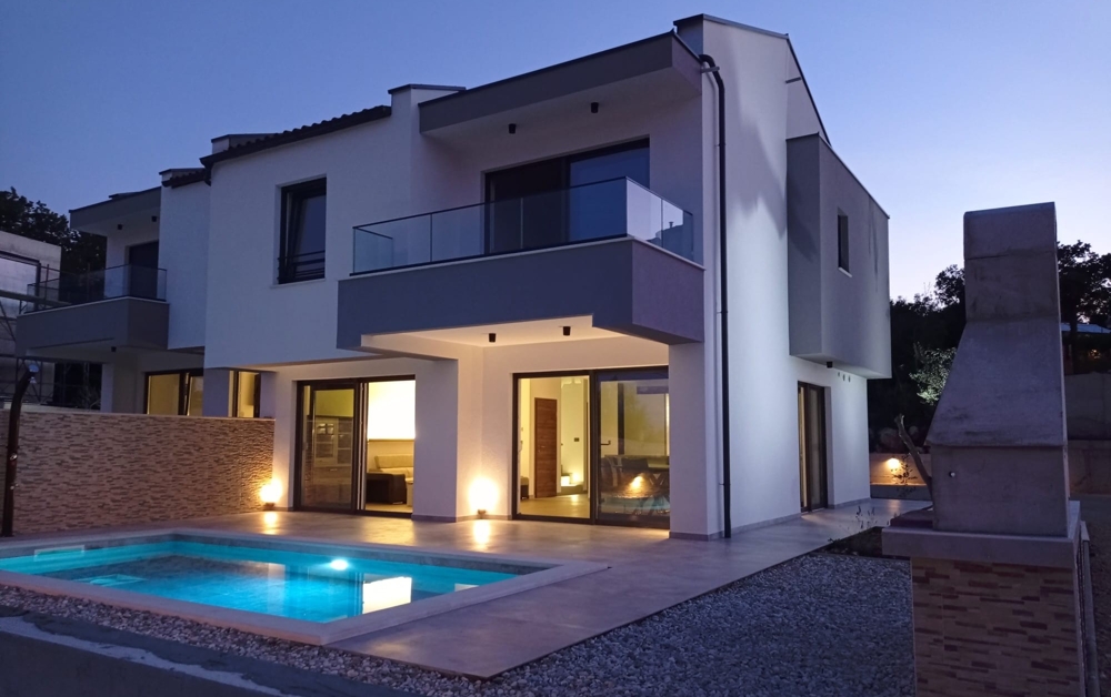 The illuminated front view of a modern property in Croatia shows the architecture and the entrance area.