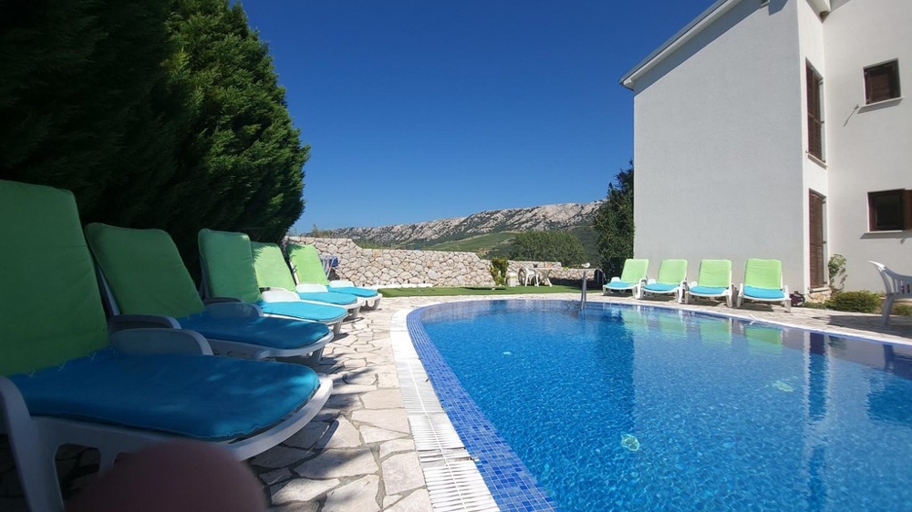Pool with sun loungers next to the house