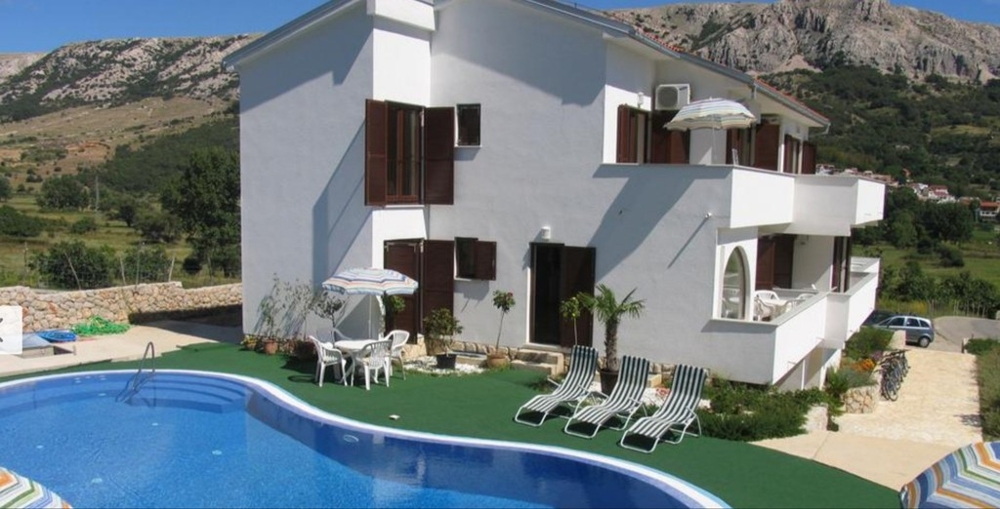 House with swimming pool, lawn and parasols