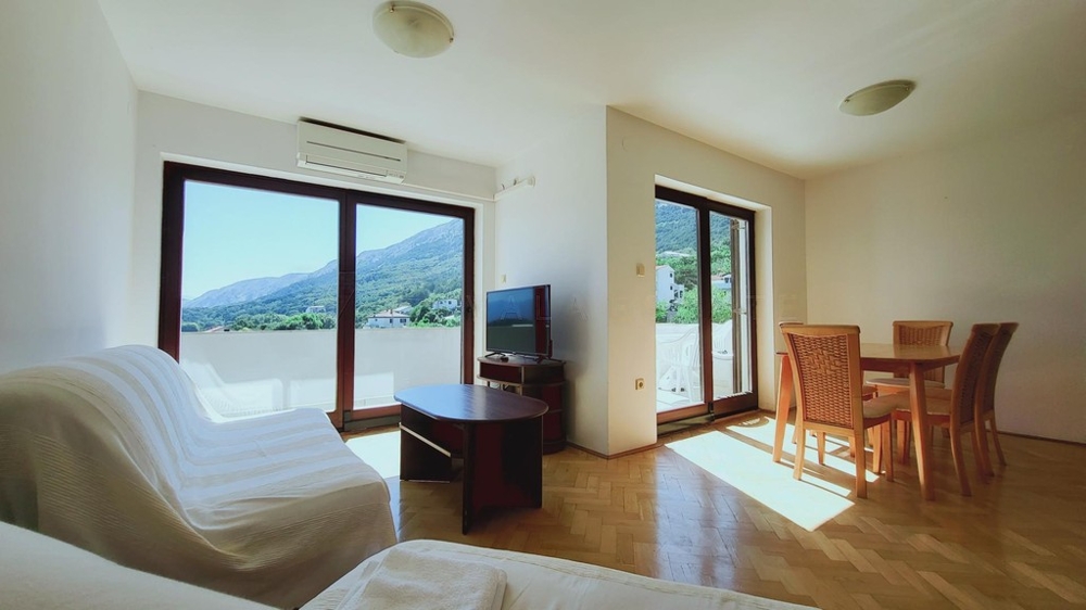 Living room with sofa, dining table and French windows to the balcony