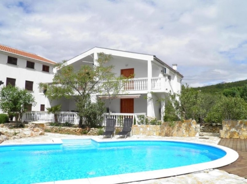 Real estate Croatia, buy a house Croatia - Panorama Scouting: Image of an attractive stone house with an adjacent pool area, surrounded by lush greenery and flowering bushes under a cloudy sky