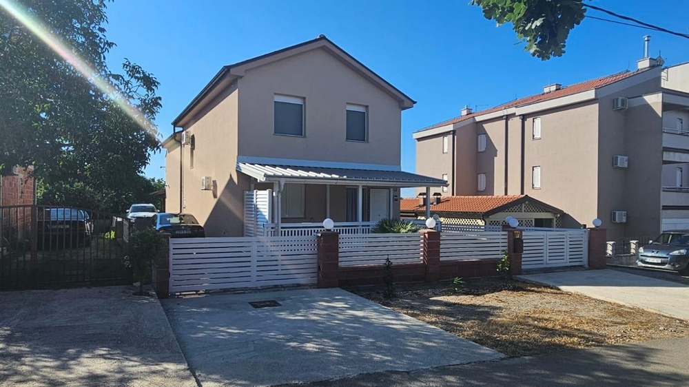 Detached house in Croatia for sale, front view with white fence and driveway.