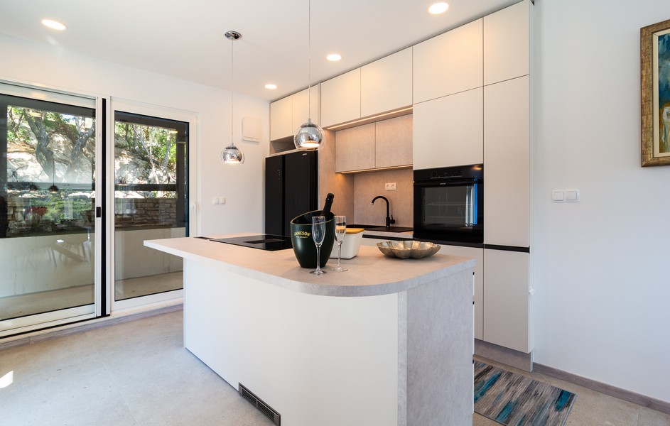 Modern fitted kitchen with cooking island and access to the terrace