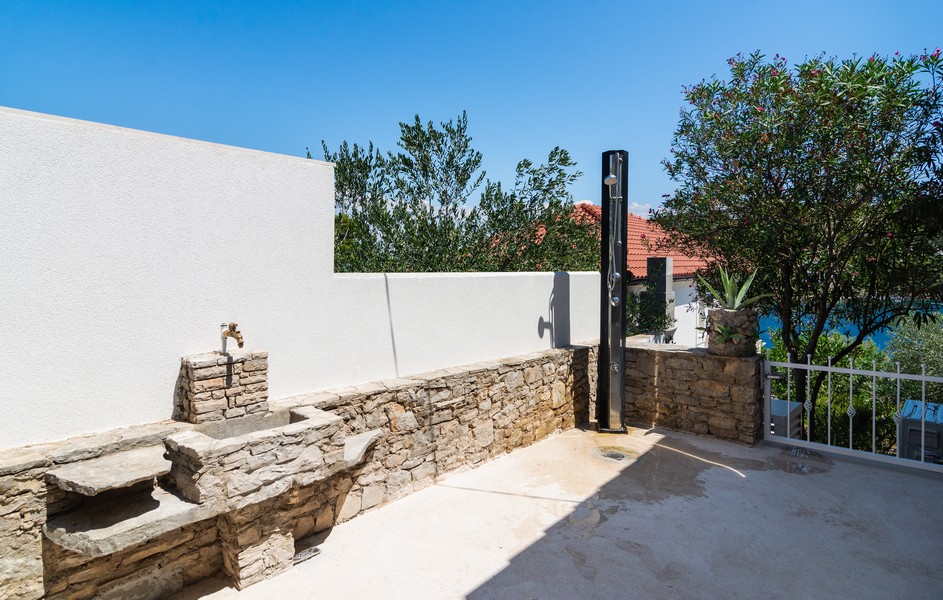 Outside with a stone seat bench, sink and outdoor shower