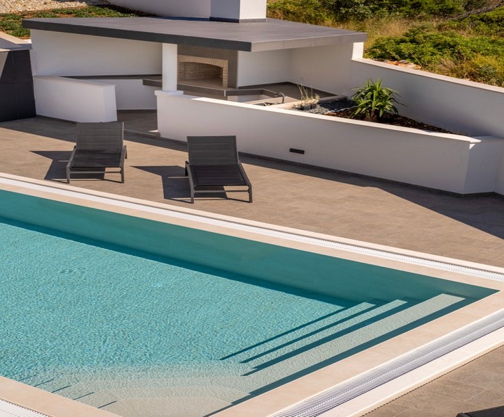Pool area with sun loungers and modern summer kitchen