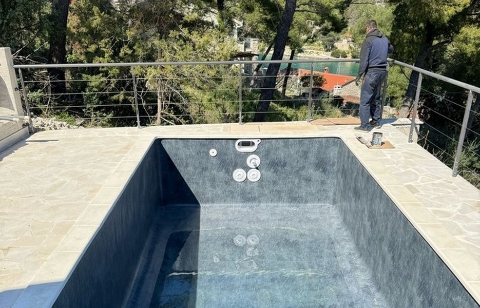 Swimming pool under construction with worker on terrace