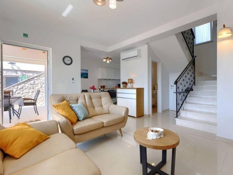 Living area with sofa, stairs and access to the terrace