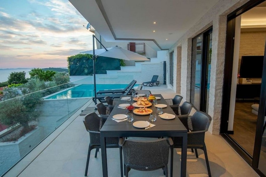 Terrace with dining table, sea view and pool in Primosten