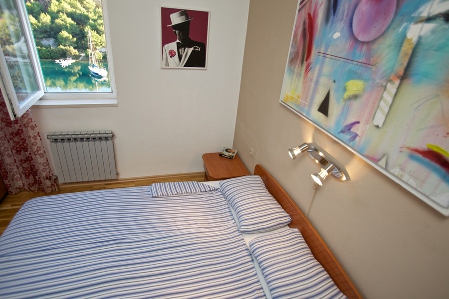 Bedroom with window view of bay and sailboat