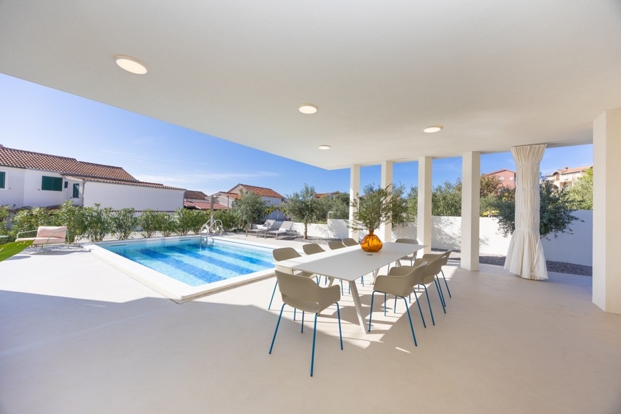 Covered terrace with dining area and view of the pool