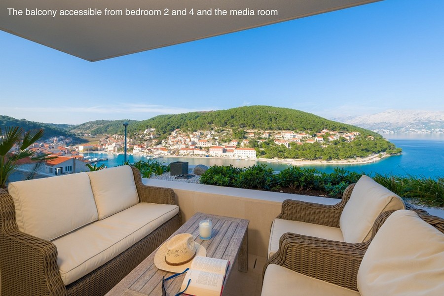 Covered balcony with seating area and views of the bay and town