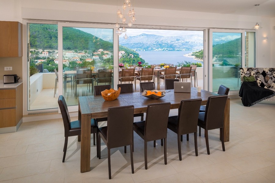Living area with large dining table and panoramic windows with sea views