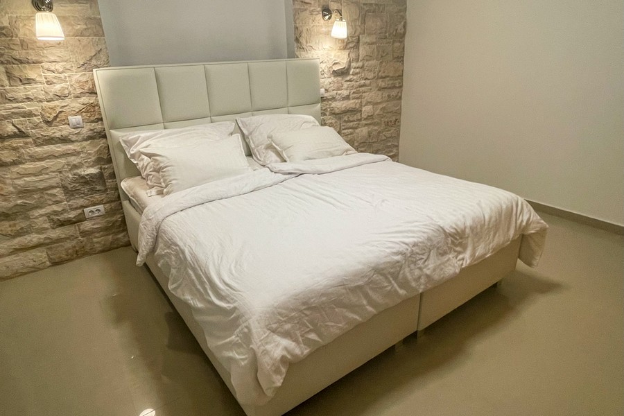 Bedroom with double bed and natural stone wall