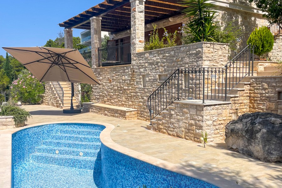 Swimming pool with sun terrace in front of the stone villa by the sea