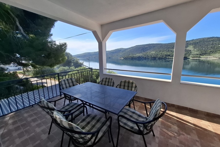 Covered outdoor area with dining table and sea views