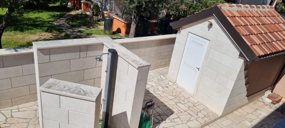 Outdoor shower and courtyard area with outbuilding in a location near the beach in Croatia