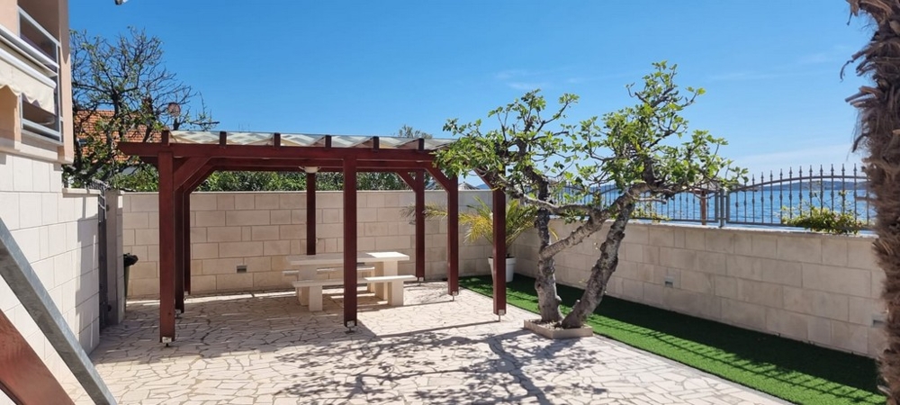 Well-kept outdoor area with seating under a pergola and Mediterranean plants
