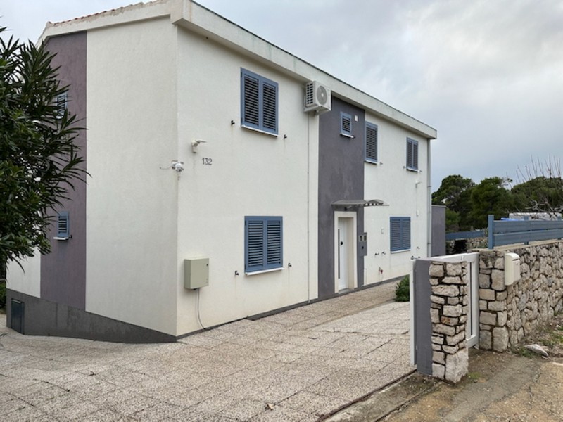 House facade with entrance area and parking space on a fenced property in Croatia