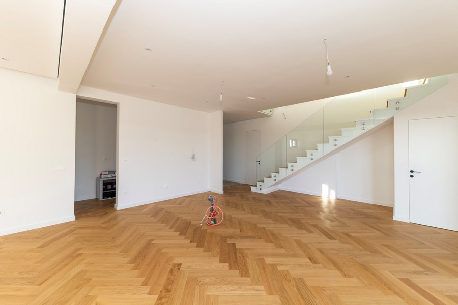 Bright living room with parquet floors and modern glass staircase