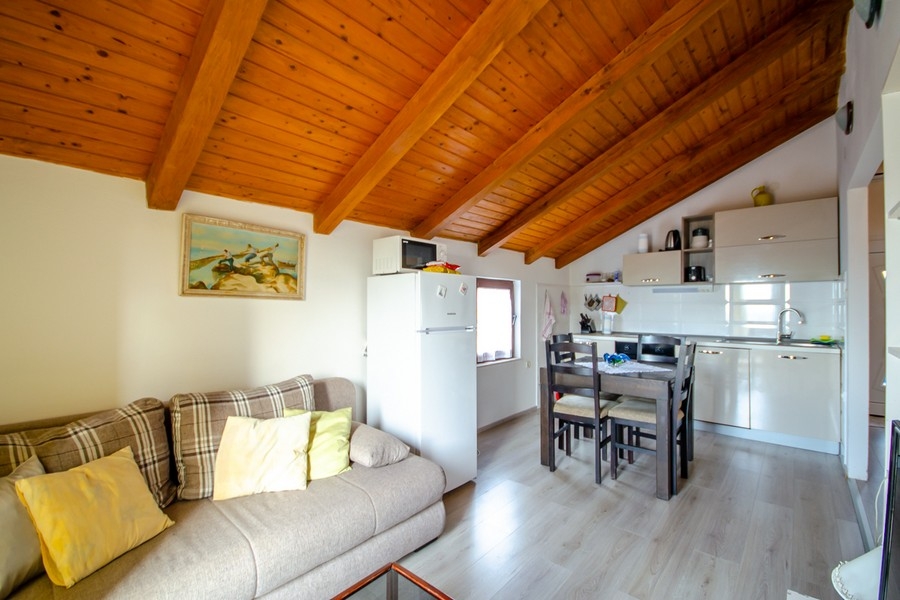 Living and dining area with open kitchen and wooden beamed ceiling
