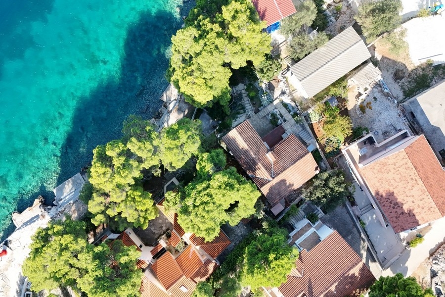 Aerial view of a property in the first row to the sea with pine trees