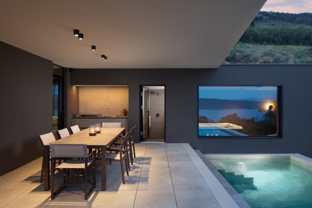 Outdoor area with pool and covered dining area in the evening atmosphere