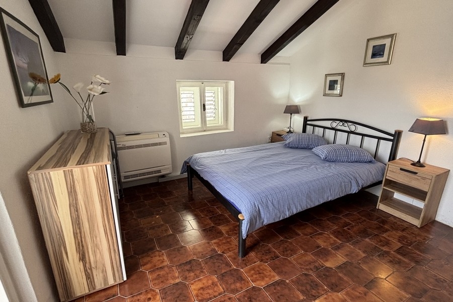 Bright bedroom with exposed wooden beams in Dalmatian stone house