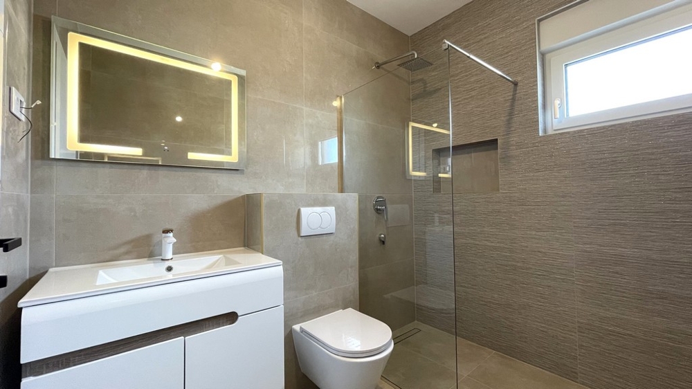 Bathroom with vanity and illuminated mirror