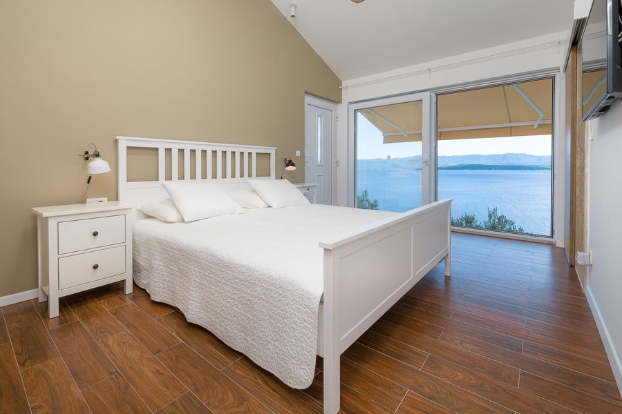 Bedroom with double bed and large windows facing the sea