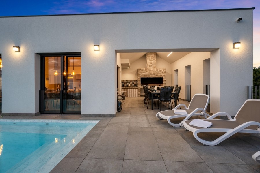 Covered terrace with sun loungers and pool in the evening