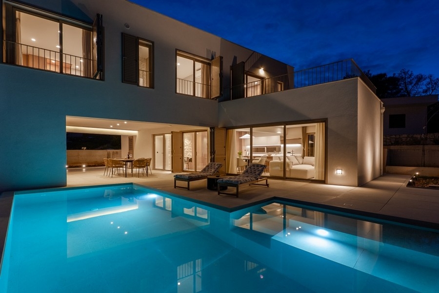 Illuminated villa with pool at dusk