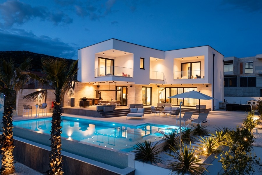 Illuminated luxury villa with infinity pool at dusk