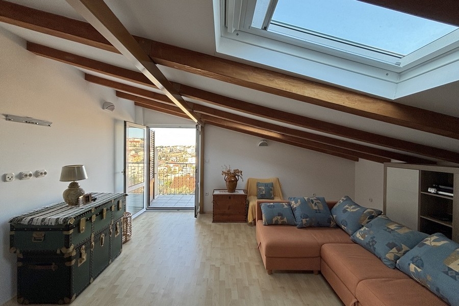 Living area in the attic with a sloping ceiling and wooden beams
