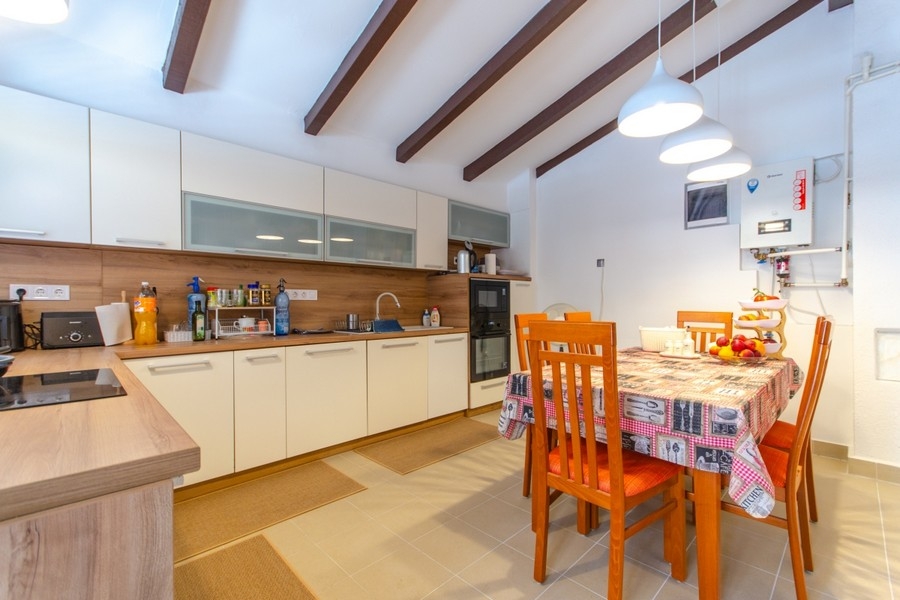 Kitchen with dining table under wooden beamed ceiling