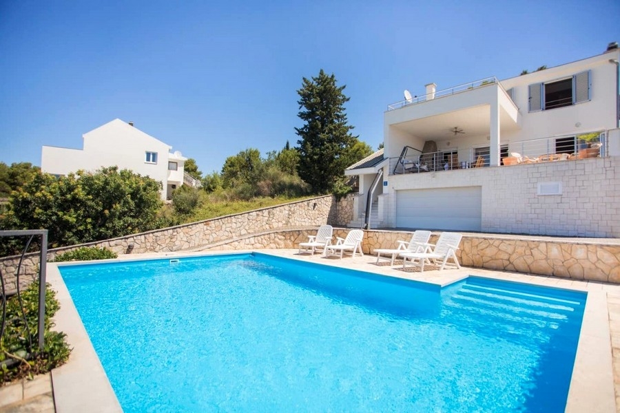 Large pool with sunbeds in front of the villa
