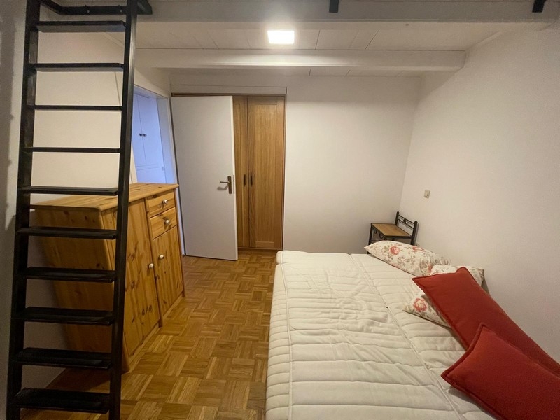 Bedroom with wooden furniture and ladder to the gallery