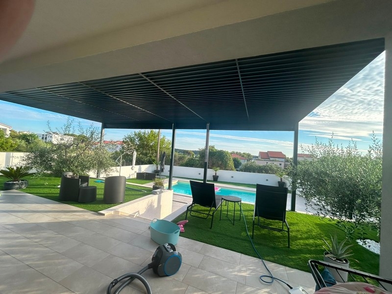 Covered terrace with seating area, lawn and pool
