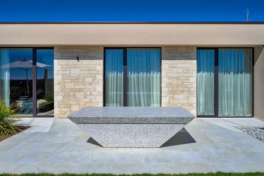 Terrace with stone table and glass front of the villa