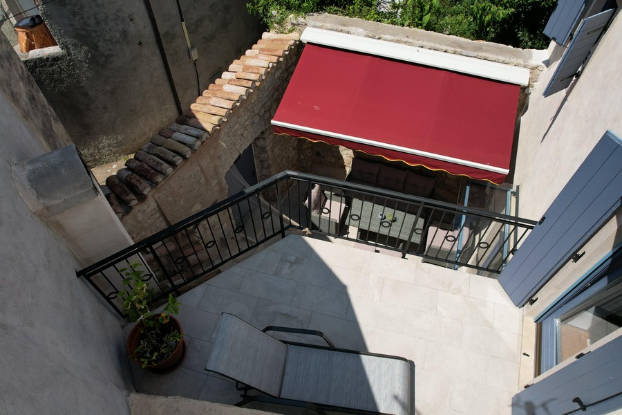 Terrace with red awning and seating area in the courtyard