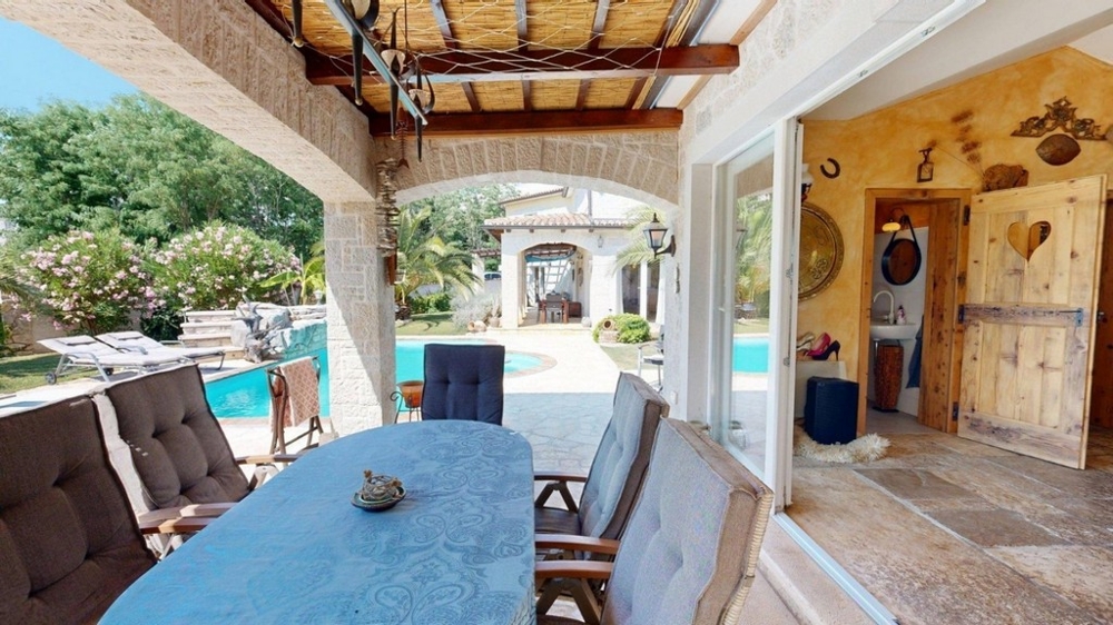 Covered terrace of the Konoba with dining table and view of the pool