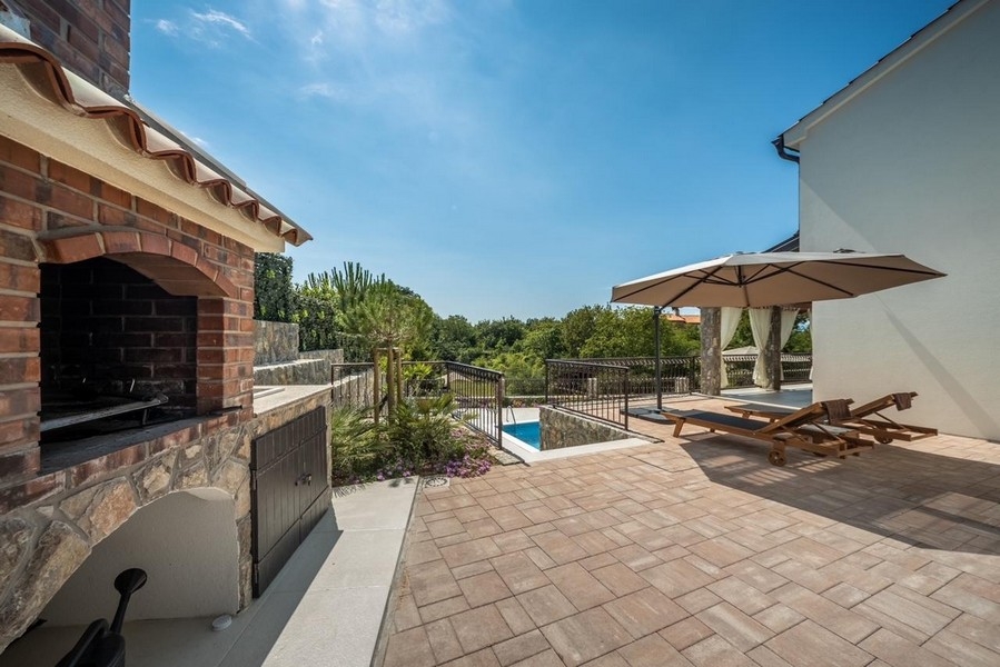 Covered patio with outdoor fireplace and pool views