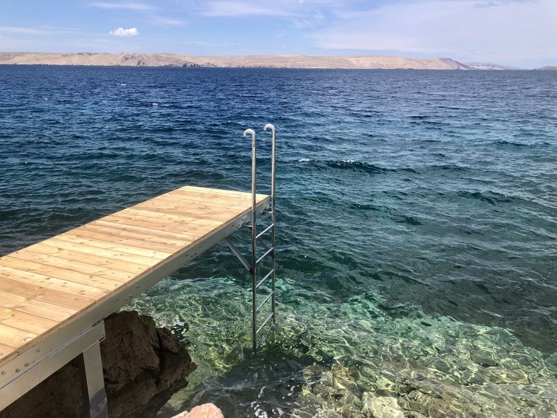 Bathing jetty with ladder into the clear sea