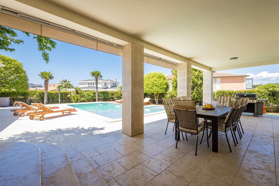 Covered terrace with dining table by the pool