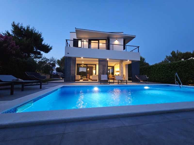 Illuminated villa with swimming pool in the evening